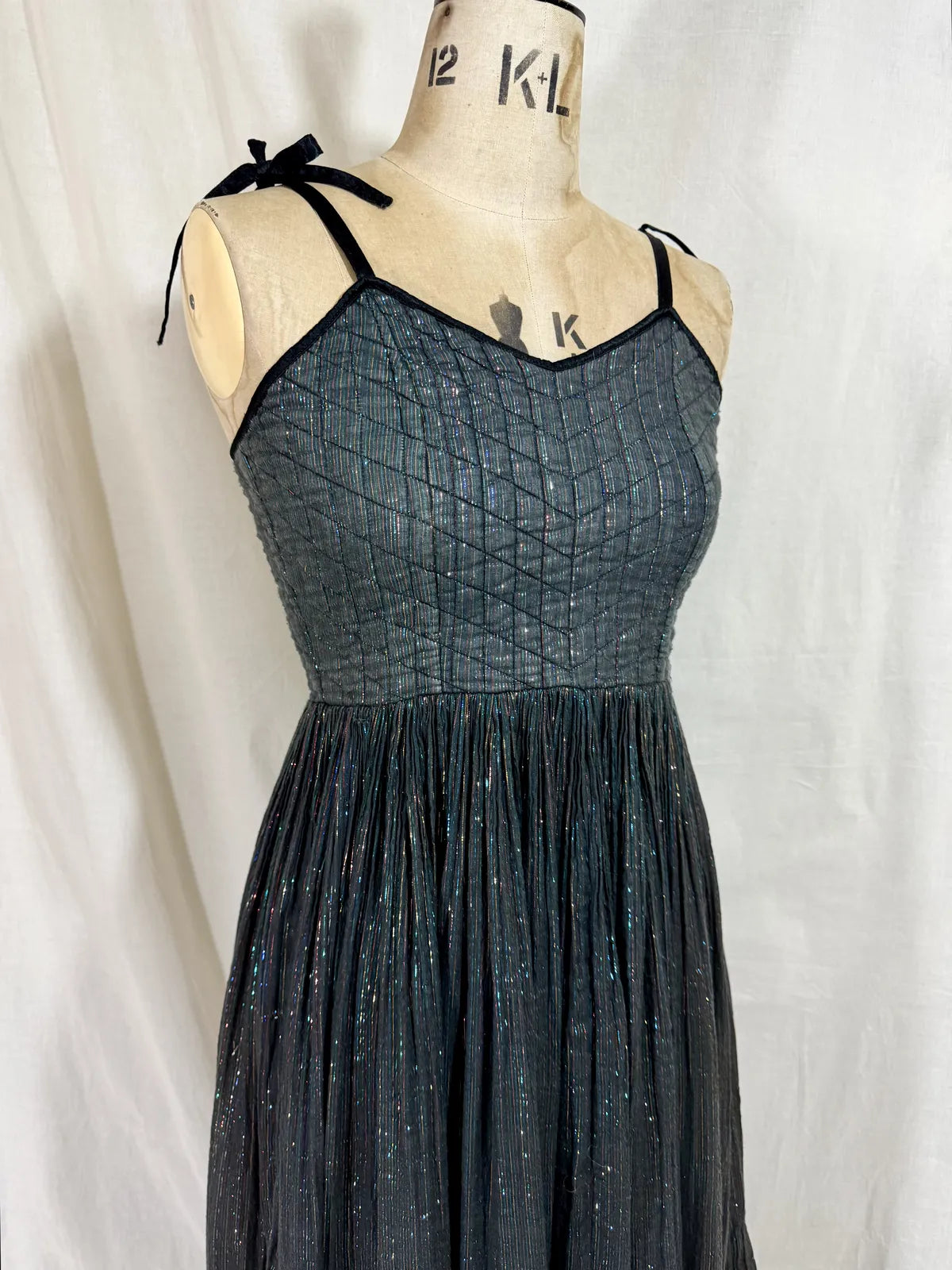 Black metallic cotton gauze dress on a mannequin against a white curtain background