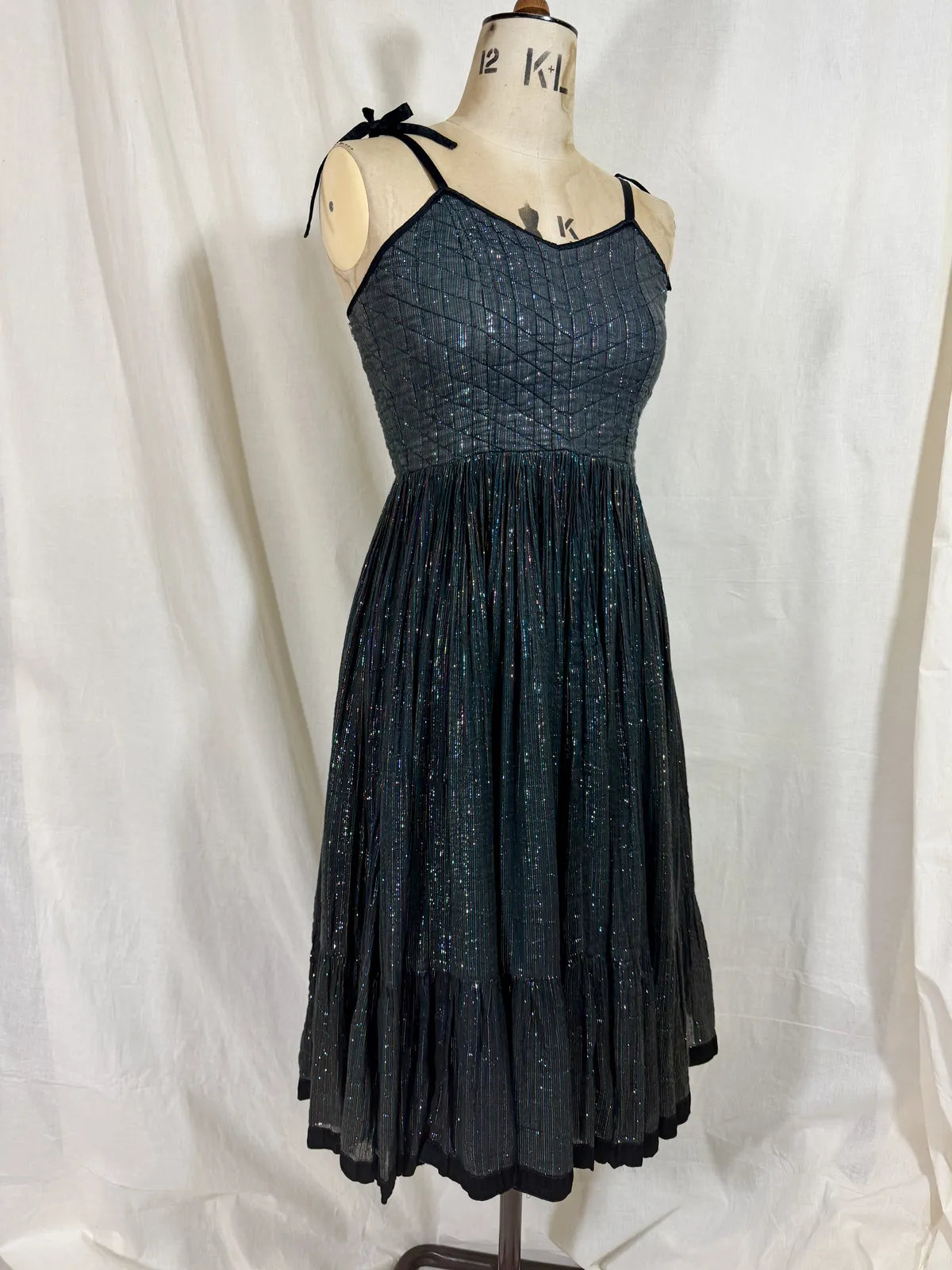 Black metallic cotton gauze dress on a mannequin against a white curtain background