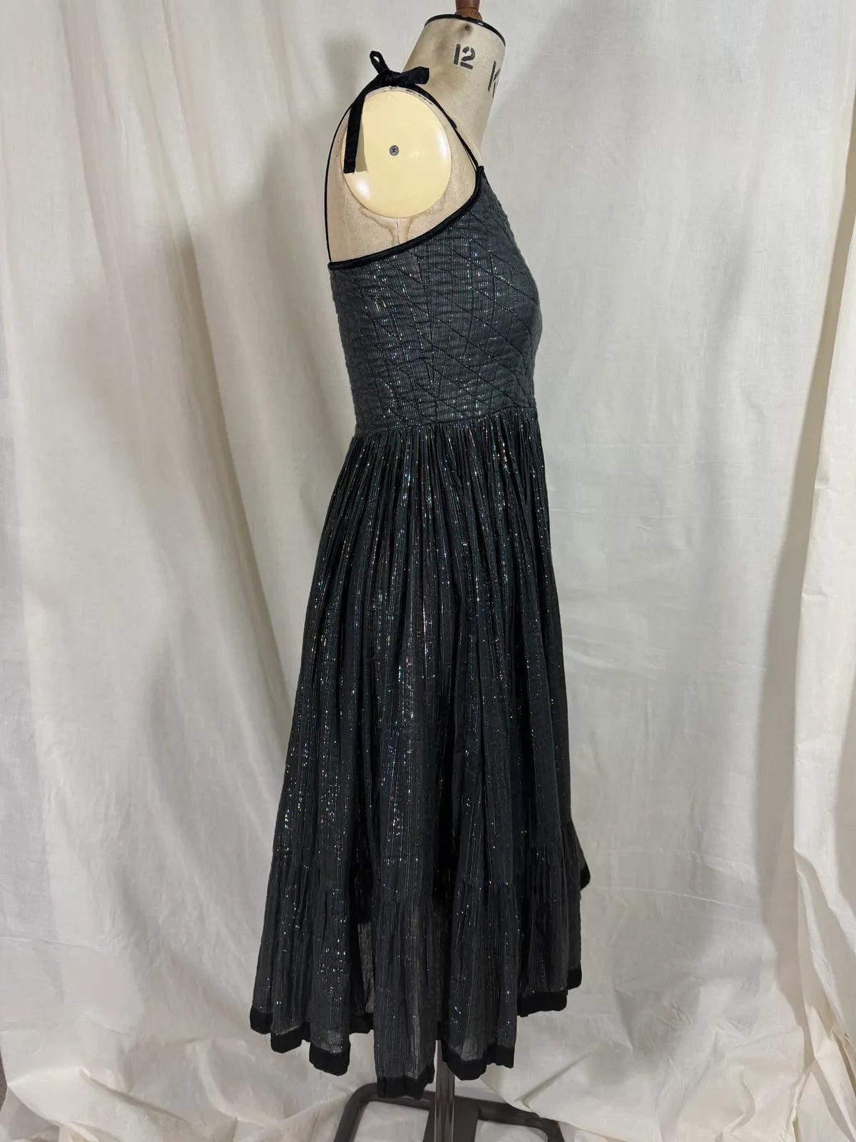 Black metallic cotton gauze dress on a mannequin against a white curtain background
