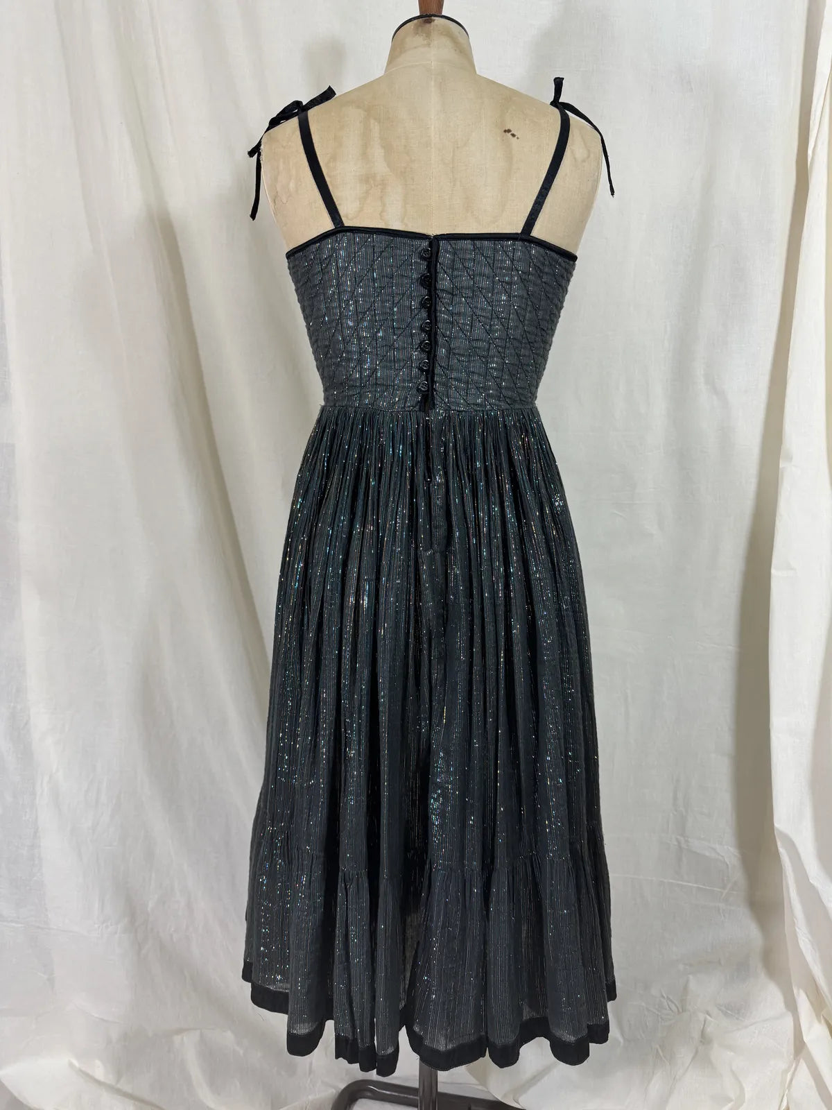 Black metallic cotton gauze dress on a mannequin against a white curtain background