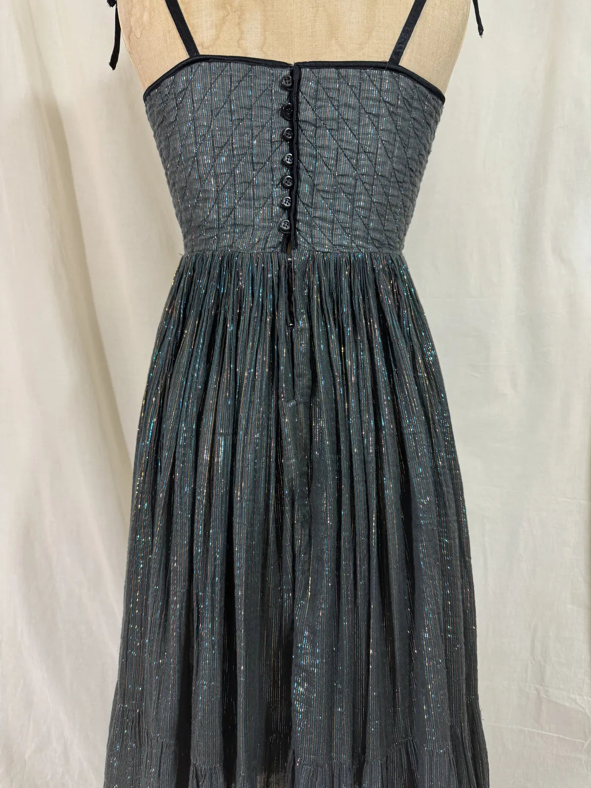 Black metallic cotton gauze dress on a mannequin against a white curtain background