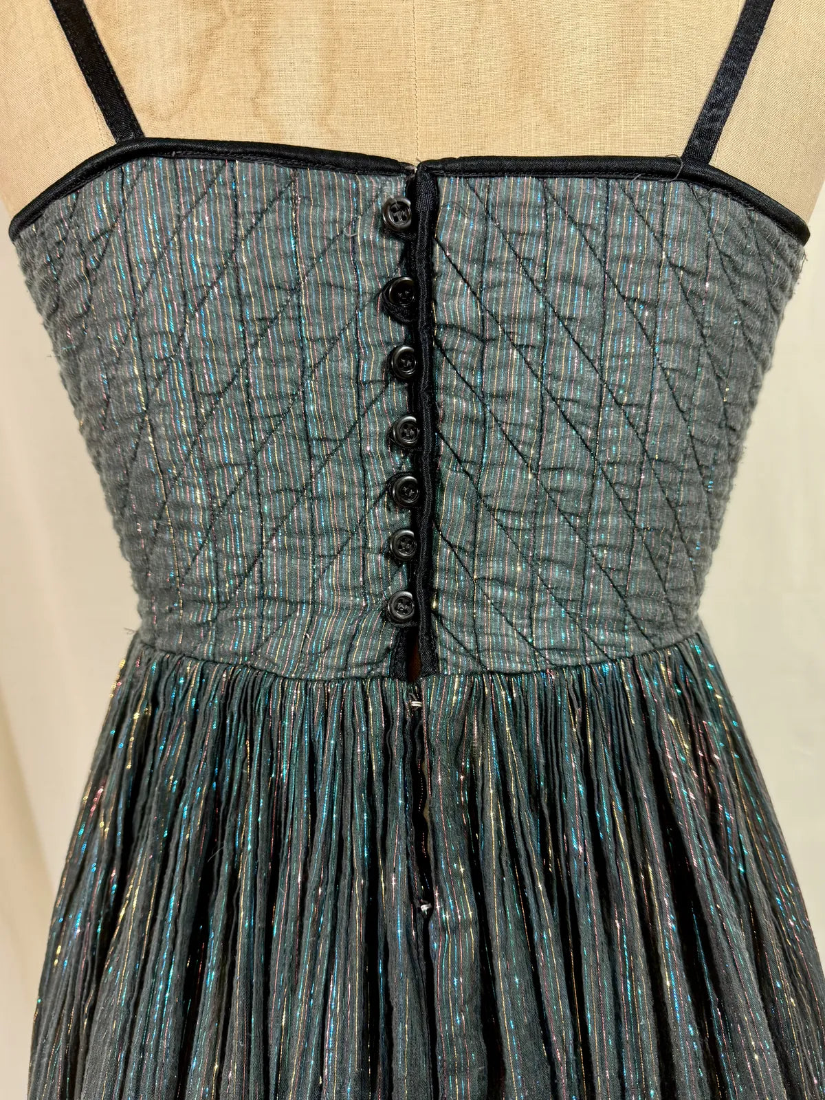 Black metallic cotton gauze dress on a mannequin against a white curtain background