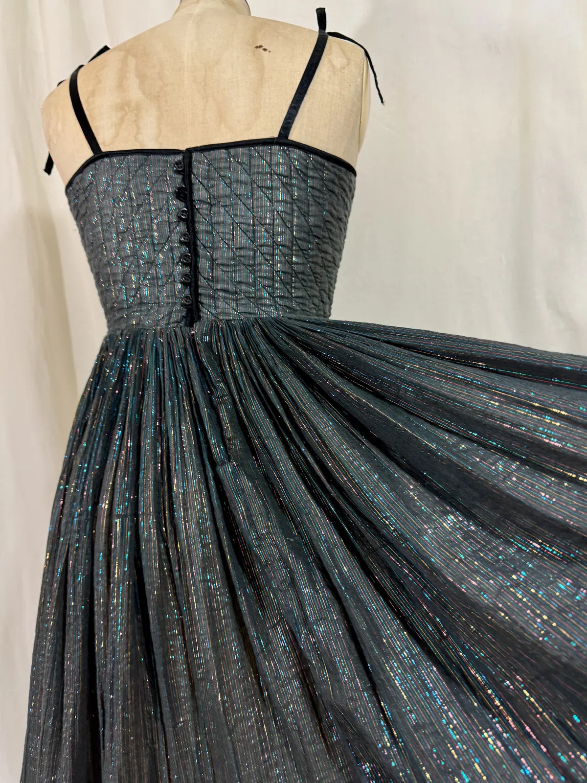 Black metallic cotton gauze dress on a mannequin against a white curtain background