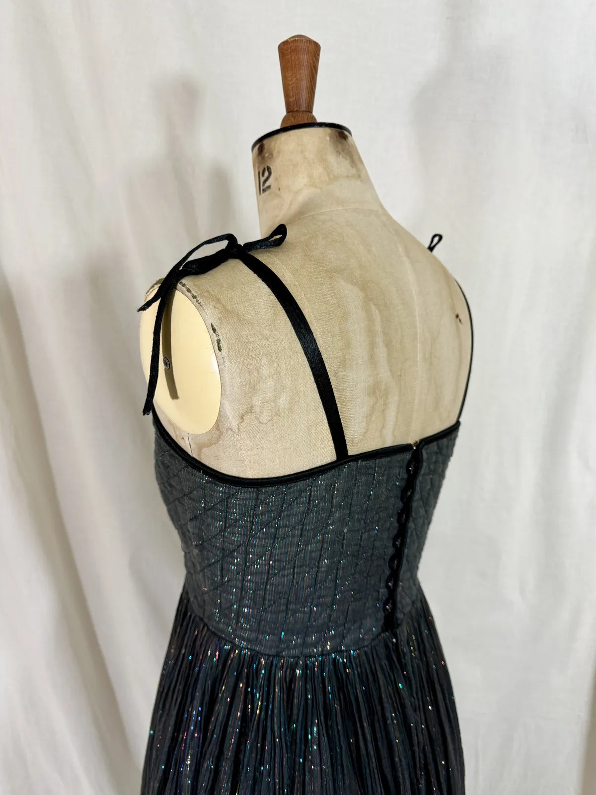 Black metallic cotton gauze dress on a mannequin against a white curtain background