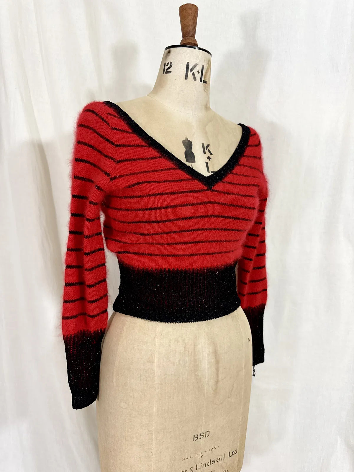 Red and black striped sweater on a mannequin against a white background