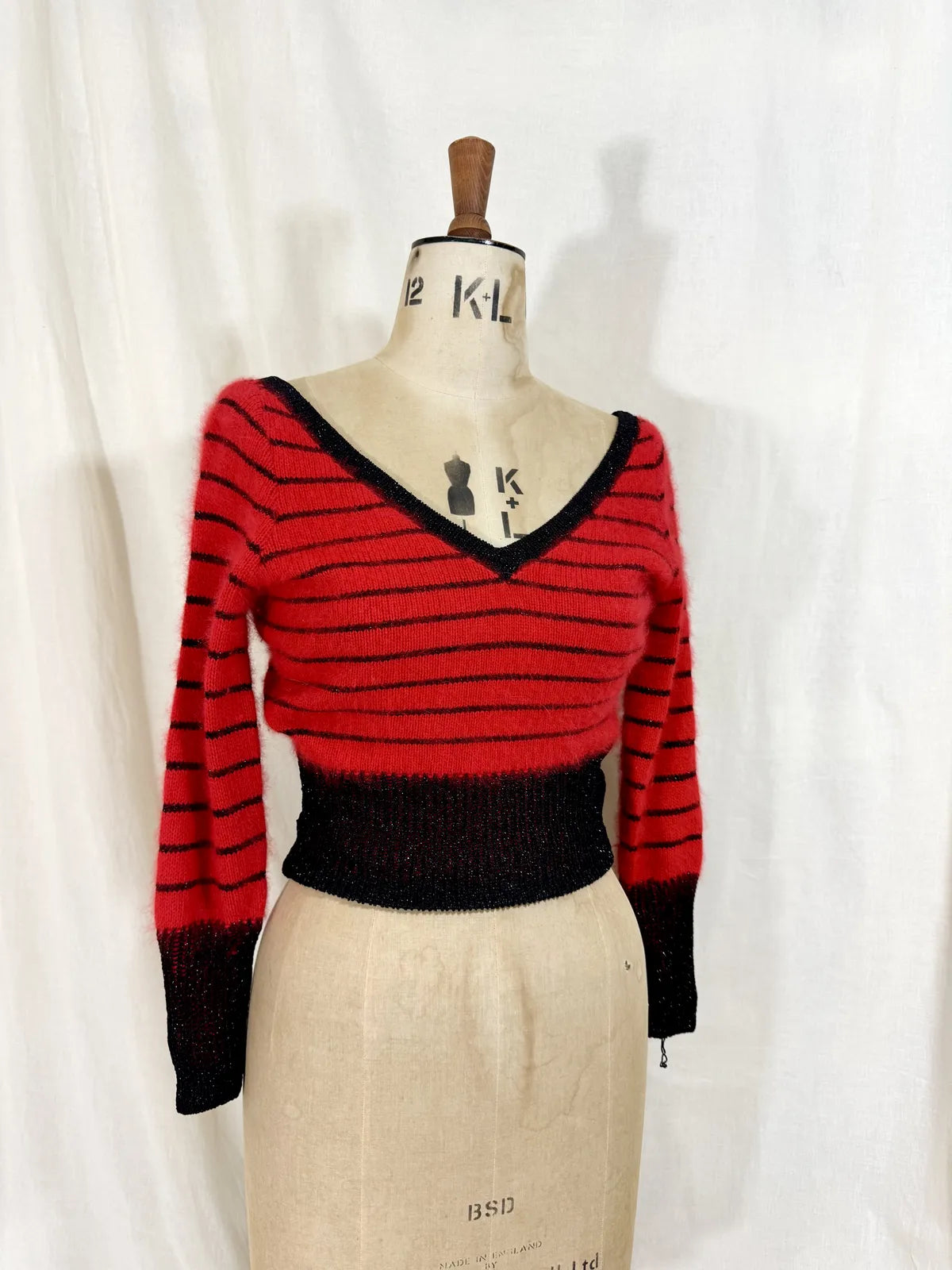 Red and black striped sweater on a mannequin against a white background
