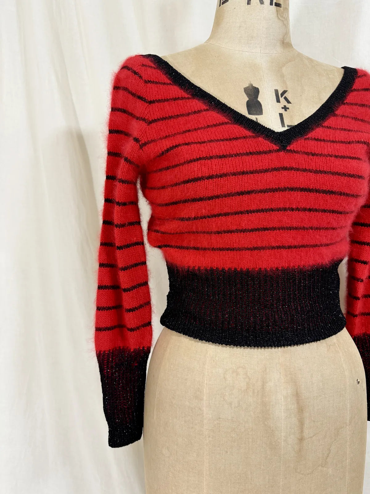 Red and black striped sweater on a mannequin against a white background