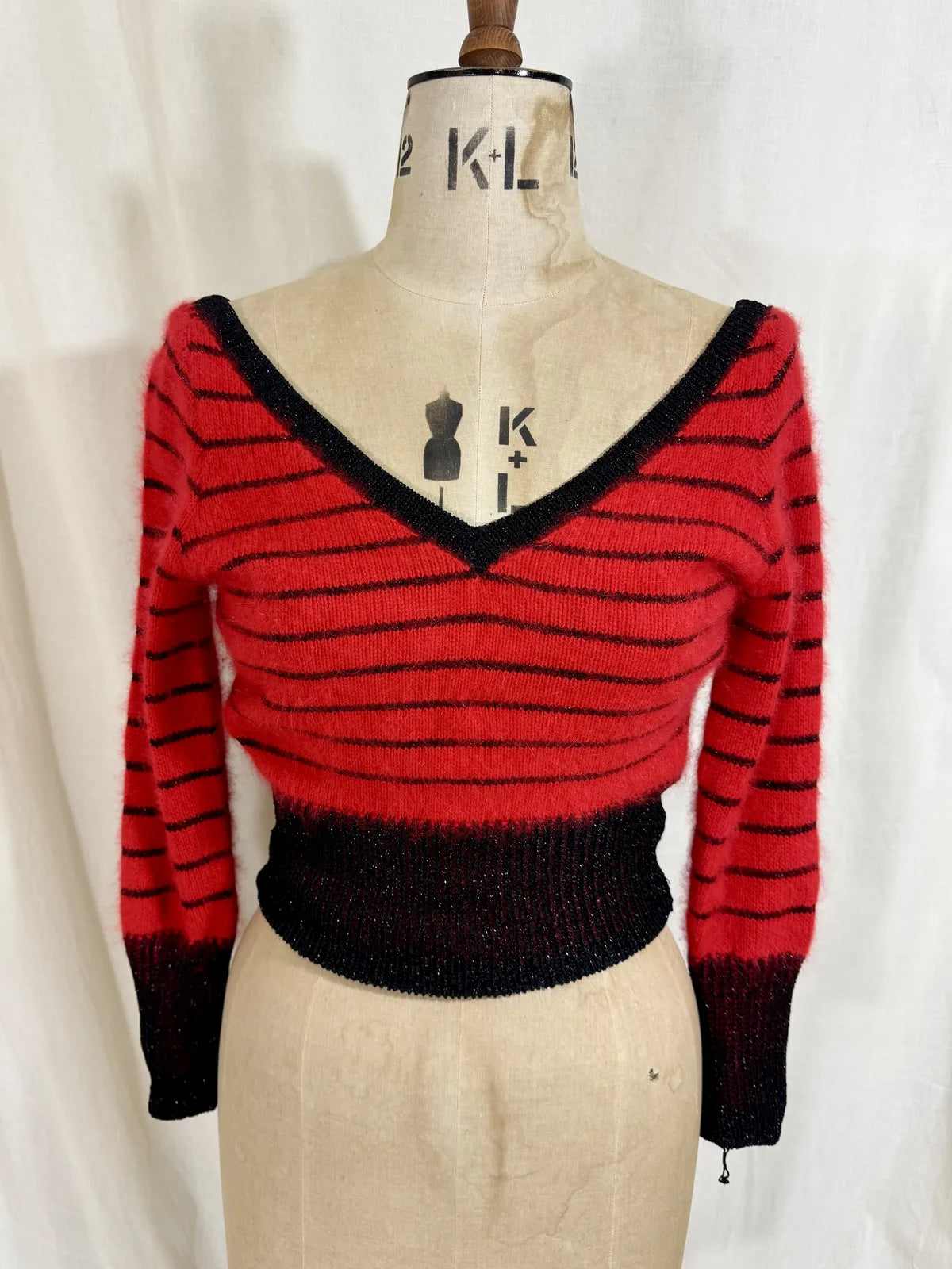 Red and black striped sweater on a mannequin against a white background