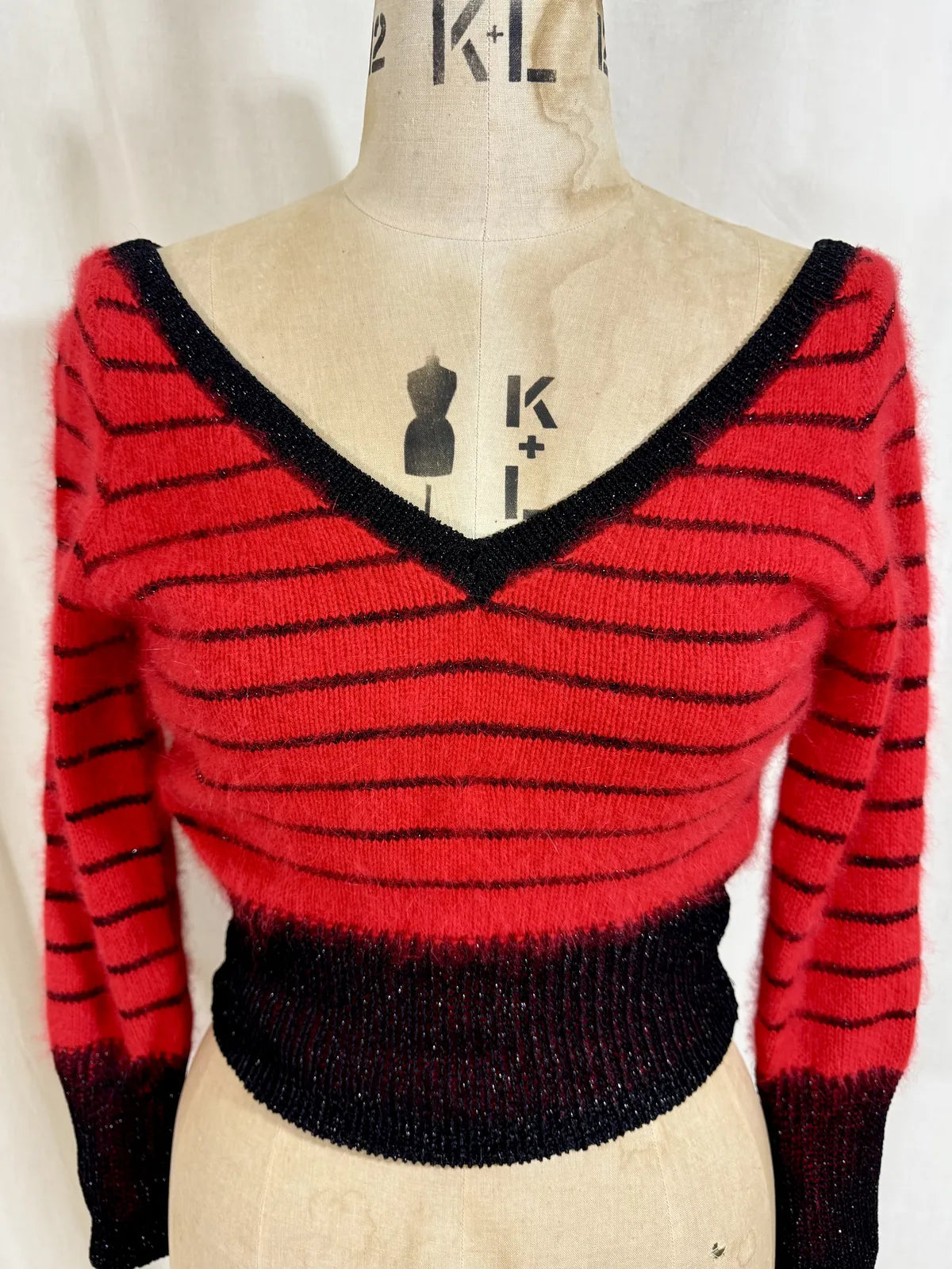 Red and black striped sweater on a mannequin against a white background
