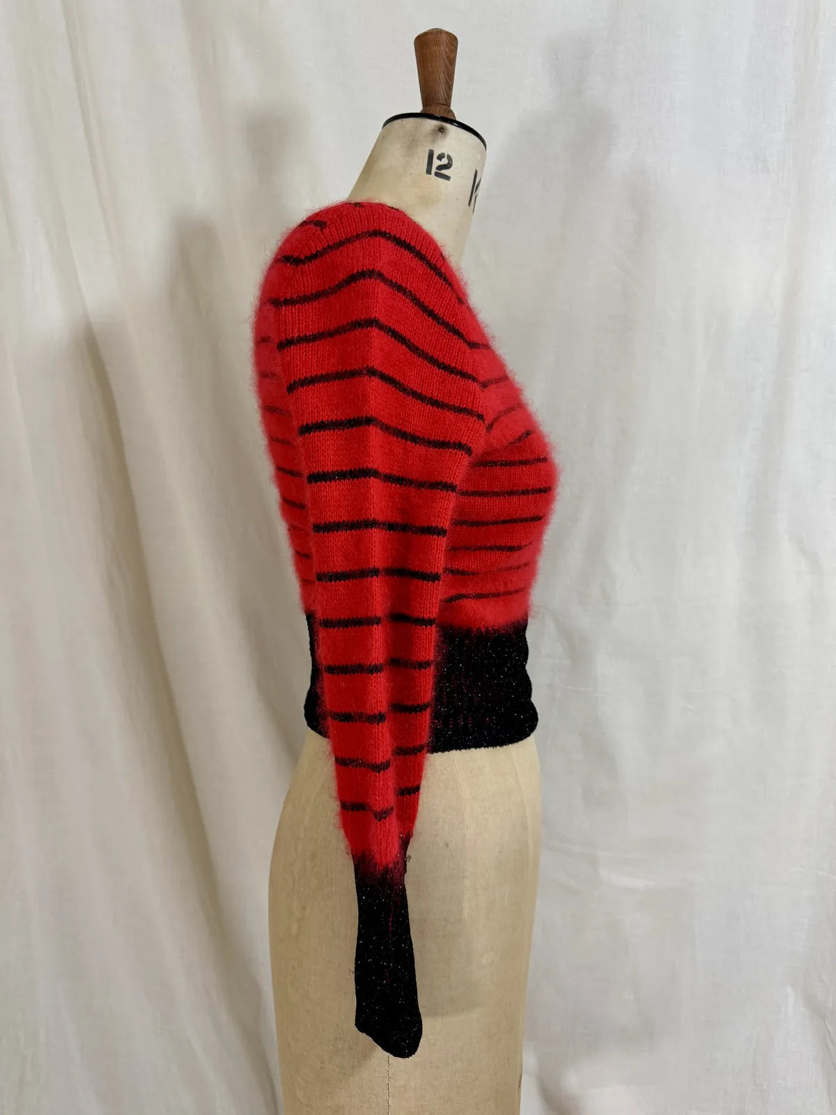Red and black striped sweater on a mannequin against a white background