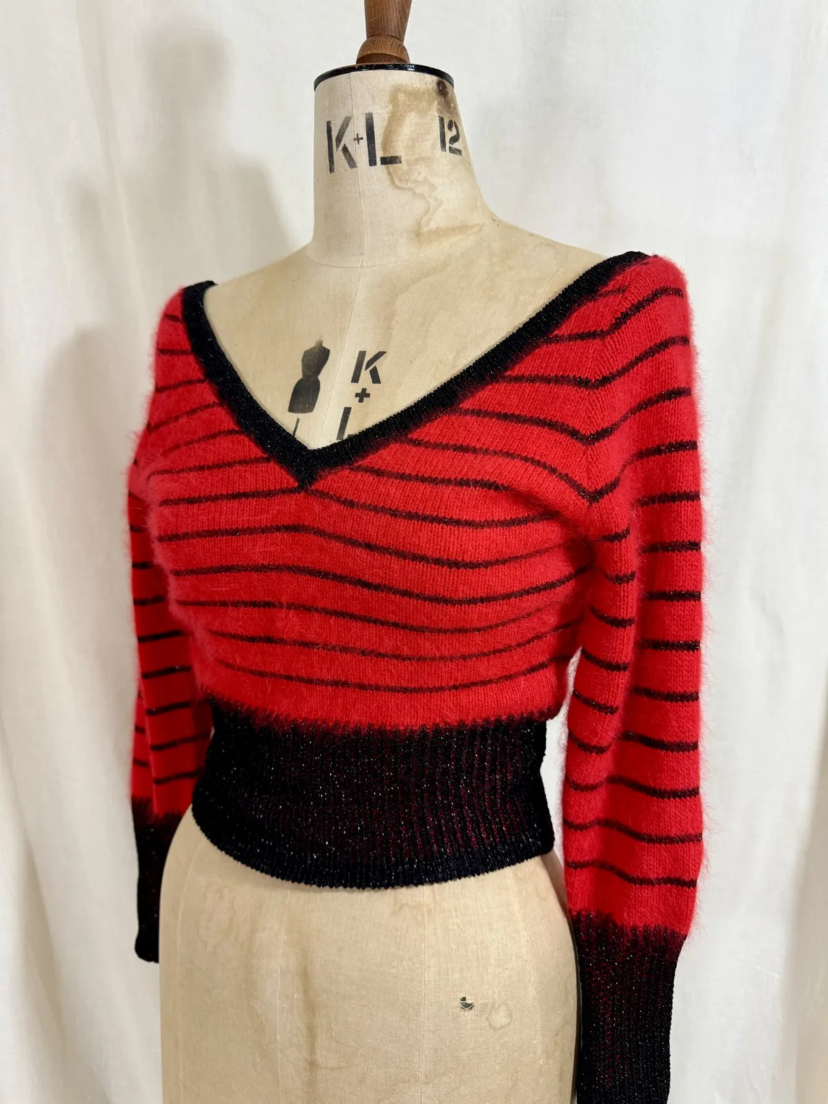 Red and black striped sweater on a mannequin against a white background
