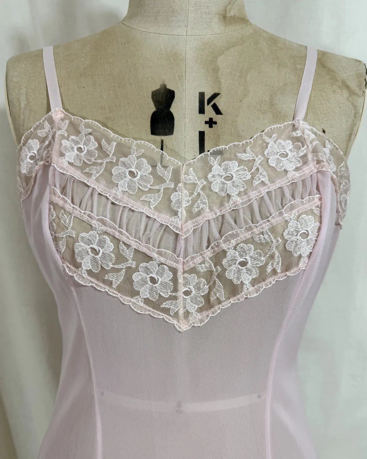 Pink slip dress with lace details on a mannequin against a white 