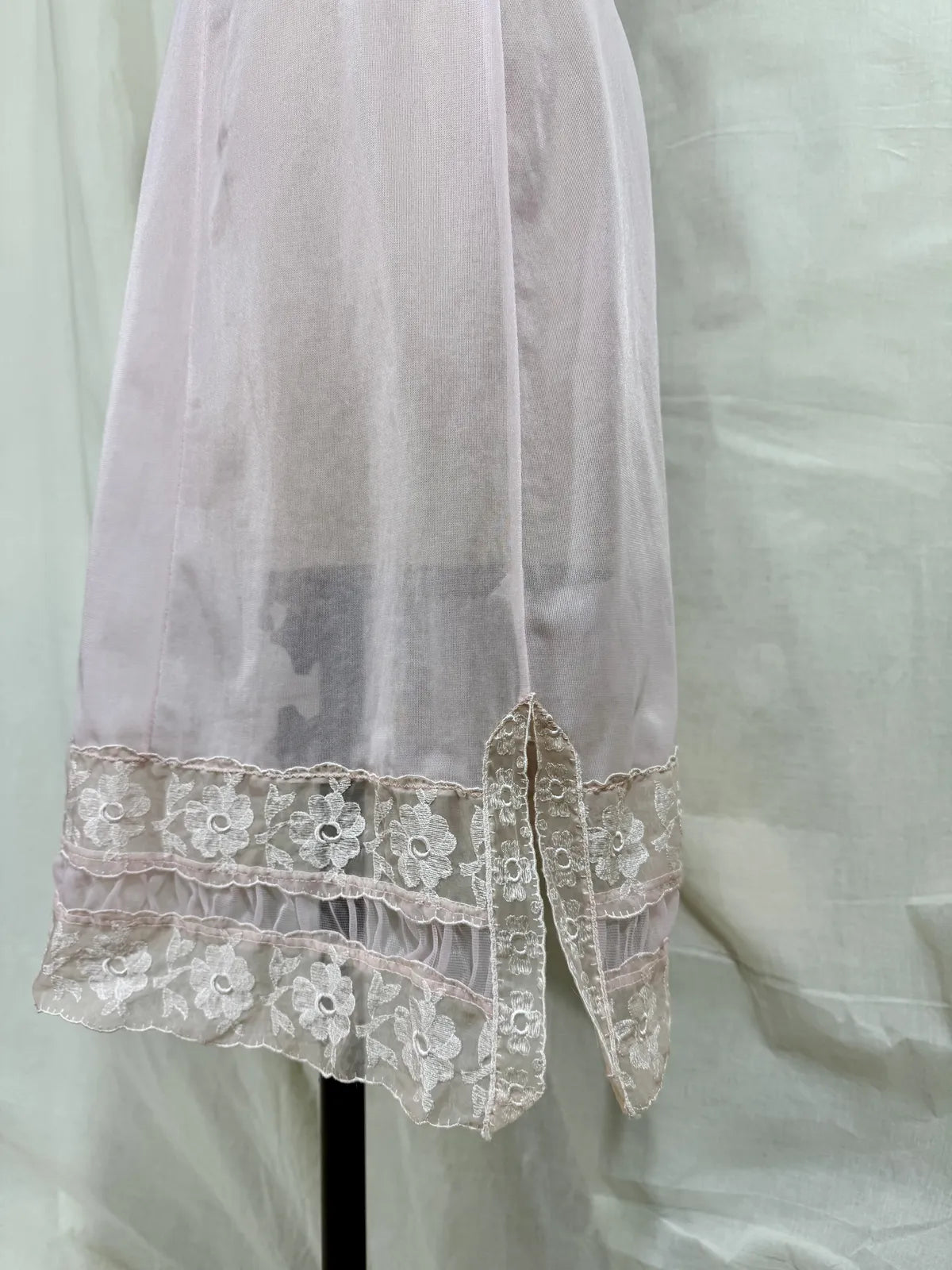 Pink slip dress with lace details on a mannequin against a white background