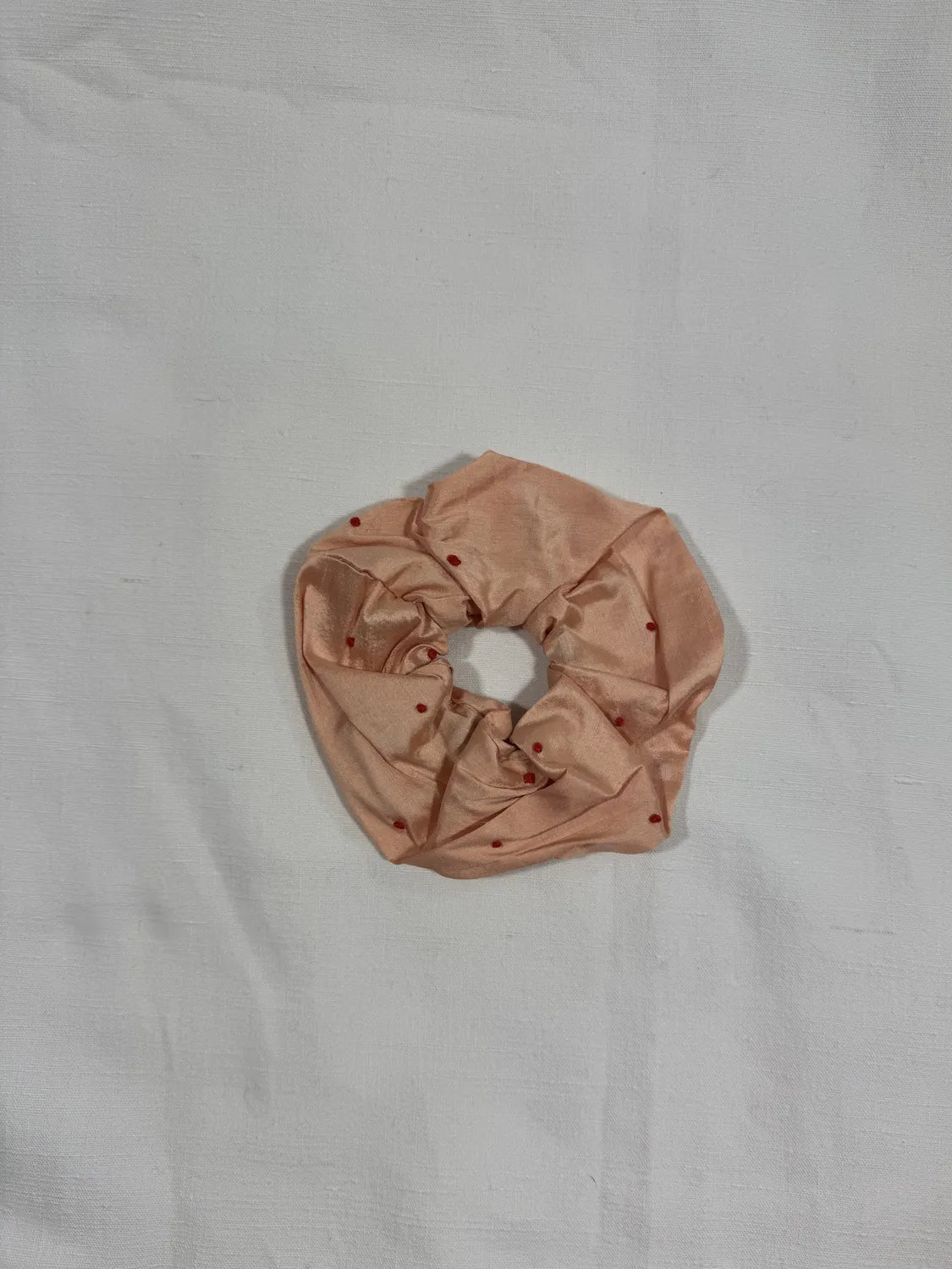 Apricot pink Dupion silk scrunchie with hand embroidery on a white background