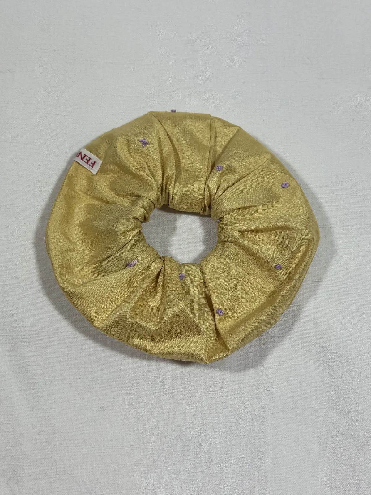 yellow silk scrunchie with hand embroidery against a white backdrop