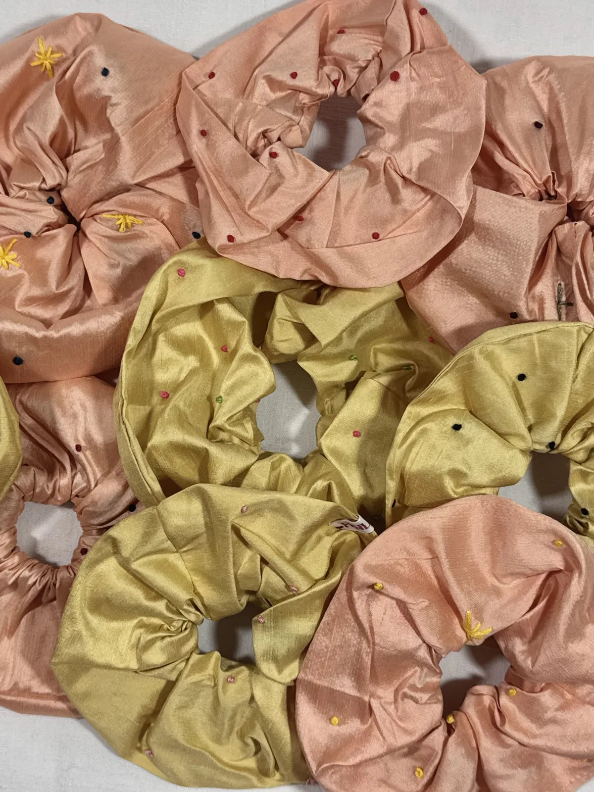yellow and pink silk scrunchie with hand embroidery against a white backdrop