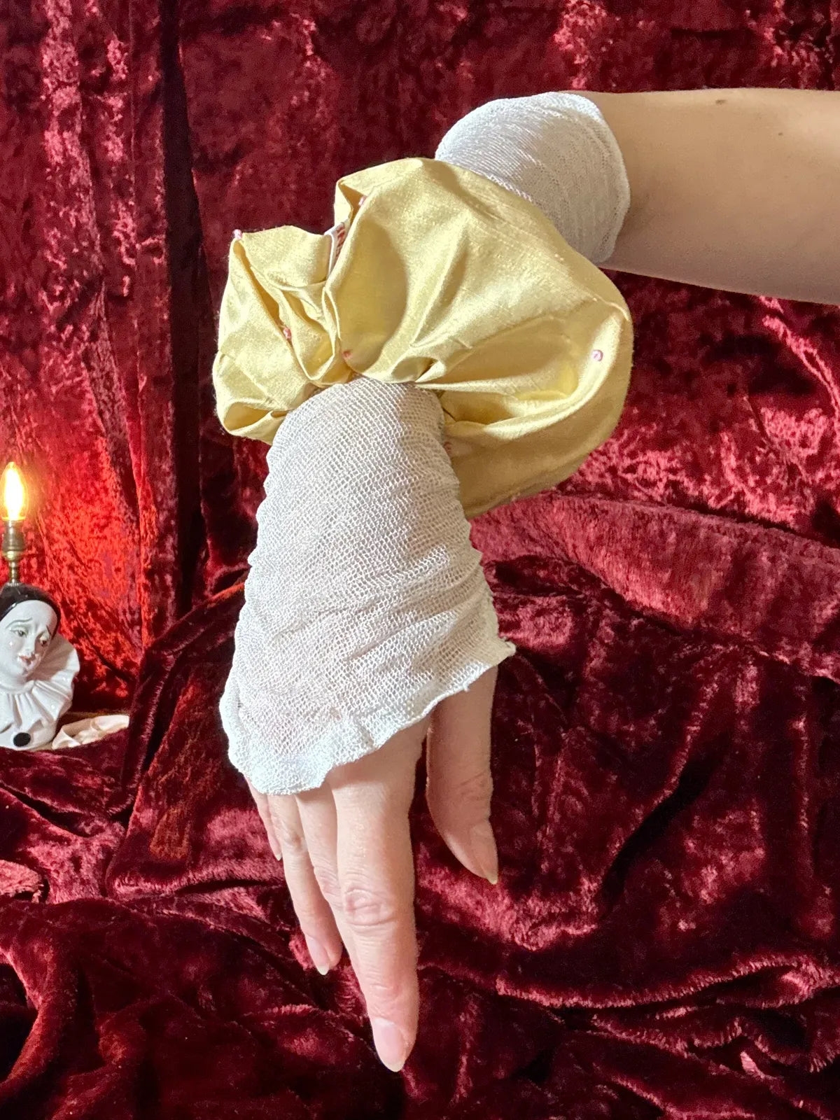 Hand with glove and silk scrunchie against red velvet background