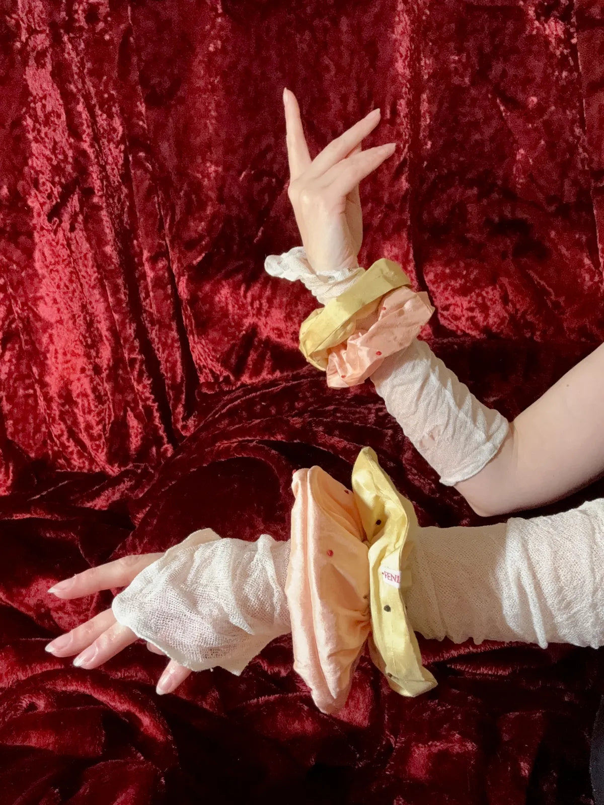 hands with gloves with silk scrunchies round wrists against red velvet backdrop