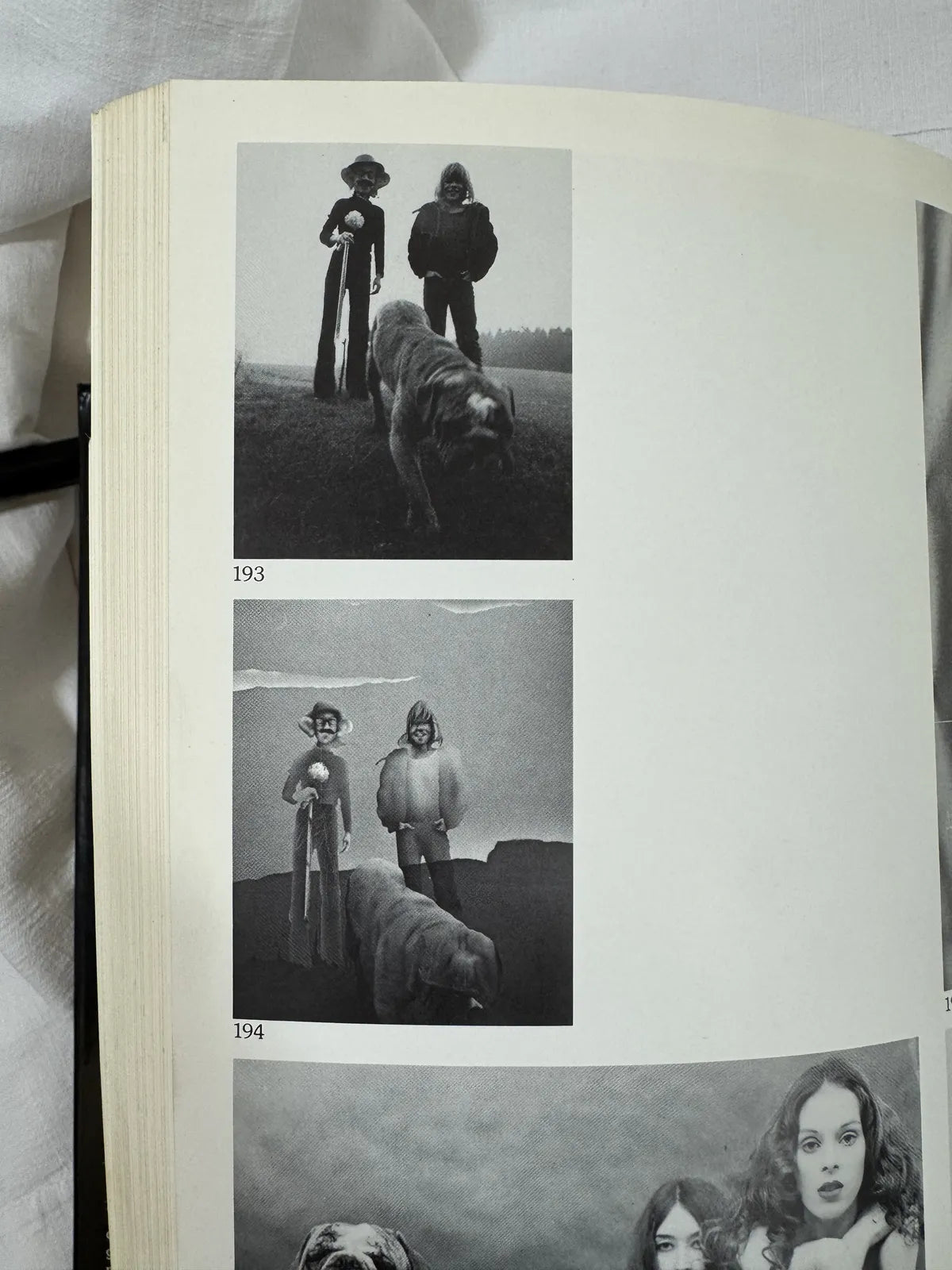 Open book with black and white photographs of people and a dog on a grassy field.