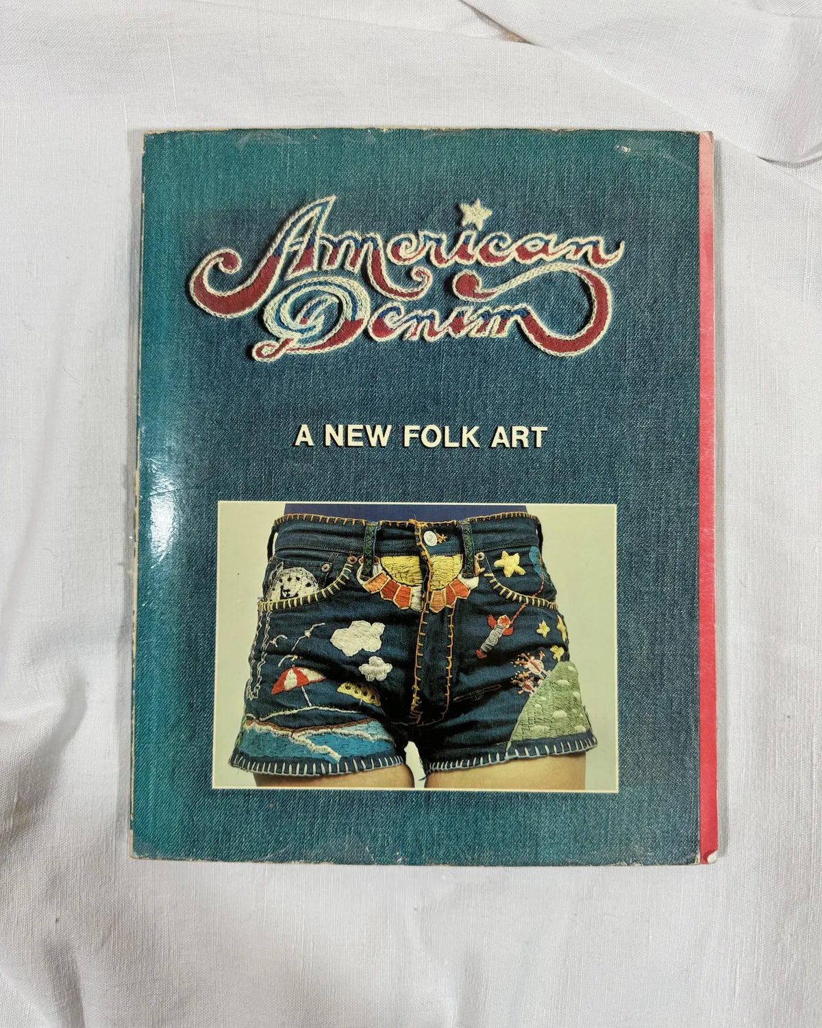 Book titled 'American Denim: A New Folk Art' on a white background